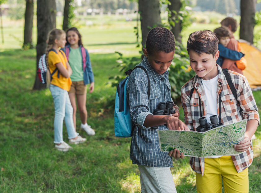 selective focus of african american kid looking at map near friend